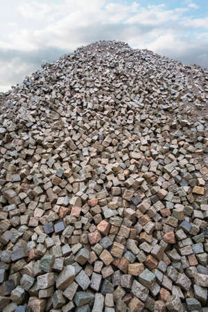 Large pile of grey natural stone cubes for making outdoor pavement tiles