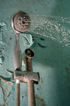 Water flowing from the shower head, green rusty grunge bathroom wall background