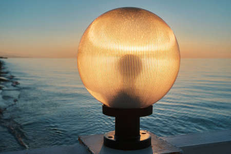Sunlight shines through a lamp on the pier, beautiful sunset sky and sea backgroundの写真素材