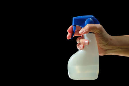 Hand holding spray bottle with antibacterial liquid, black background