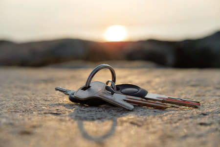 A lost keys on the ring on the rock illuminated with sun rays, blurred sunset background selective focusの写真素材