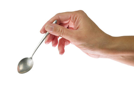 Female's hand holding steel spoon in the right hand, isolated on a white backgroundの写真素材