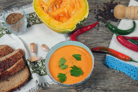 Pumpkin soup with brad onions and red pepper on the wooden table, top viewの写真素材