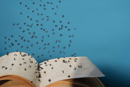 Letters of the alphabet in levitation in the air over the open book pagesの写真素材