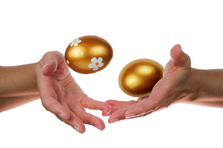 Hands of a woman perform a magic trick with the golden Easter eggs. isolated on a white backgroundの写真素材