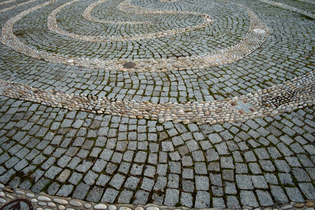 Tangled decorative path made with pebbles on the stone pavement. Background of decorative...