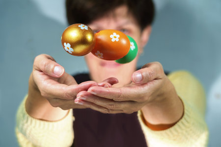 Hands of a woman perform a magic trick with the painted colorful Easter eggs, selective focus,