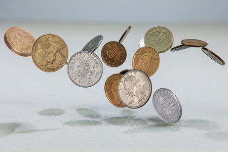 Different countries coins falling down on the white canvass surface. Coins levitating in the air