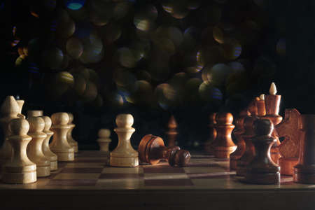 Wooden chess pieces and a chessboard on blurred dark background, selective focusの写真素材