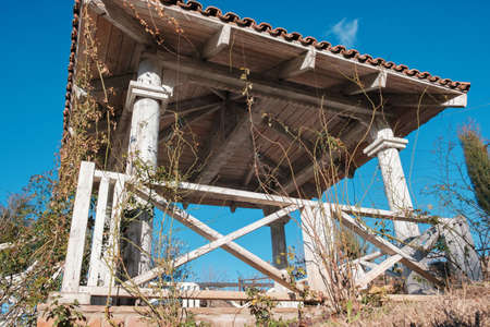 White wooden gazebo in the garden overgrown with plants on the blue sky backgroundの写真素材