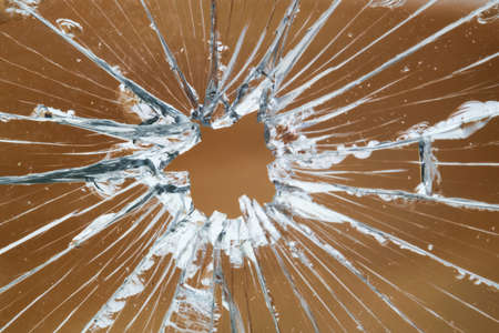 The hole in the broken and cracked glass, closeup