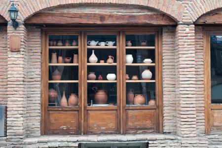 Exterior of an old brick house with wooden showcases with decorative clay ceramic pots and jugs