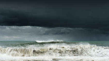 View of a stormy sea and dark cloudy sky, big waves are crashing on the shore