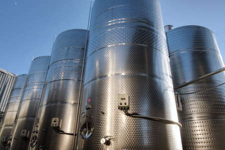 Stainless tanks for processing and fermentation wine production in the open air with blue sky background. Modern wine factoryの写真素材