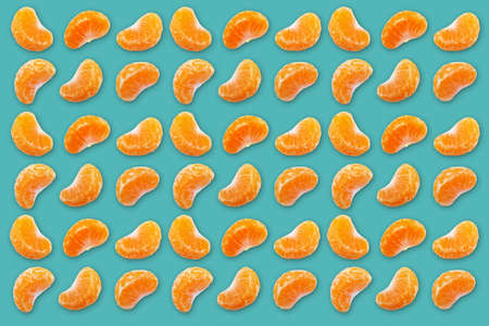 Pattern made with fresh mandarins or tangerine slices on blue background. Flat lay