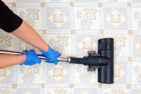 Hands with blue gloves cleaning soft surface with vacuum cleaner.の写真素材