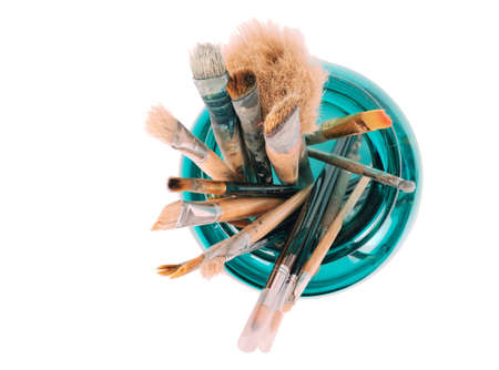 Various professional paint brushes in the green glass jar, isolated on white background