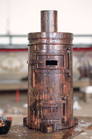 Antique iron rusty potbelly stove with blurred interior backgroundの写真素材