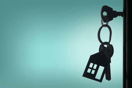 Silhouette of the keys with house keyring in the door keyhole with copy space backgroundの写真素材