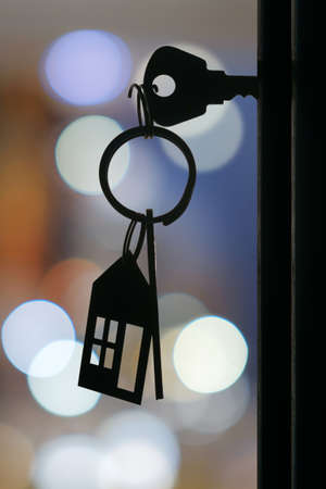 The key with keyring in the door keyhole with blurred night lights background, selective focusの写真素材