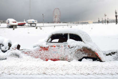 An old vintage rustic retro car in a street covered with snowの写真素材