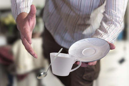 A man in stripy shirt dropping teacup with spoon, selective focusの写真素材