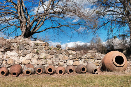 Qvevri, Georgian traditional jug for wine making near the ancient stone wall