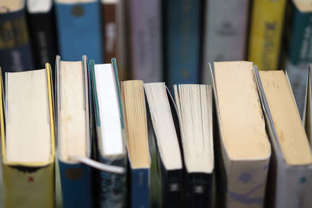 A stack of used books of different thicknesses on the shelf in the library, selective focusの写真素材