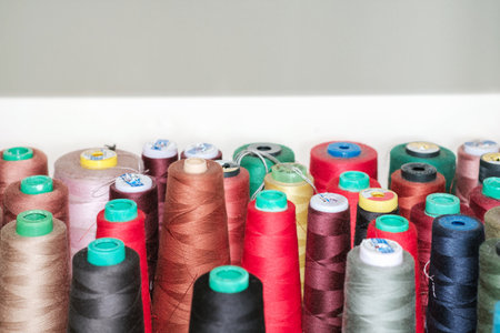Colored spools of sewing threads stand in row