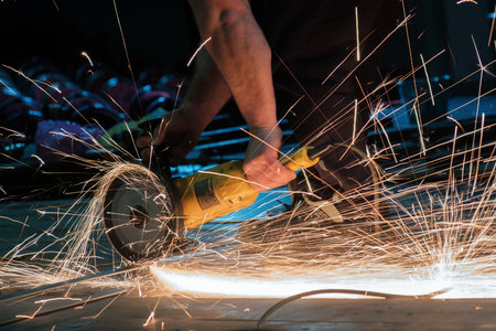 Worker working with a circular grinder on a metal with sparks flying out of themの写真素材