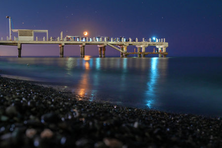 Night fishing on the pier, moon over the pier with fishing fisherman, starry sky backgroundの写真素材