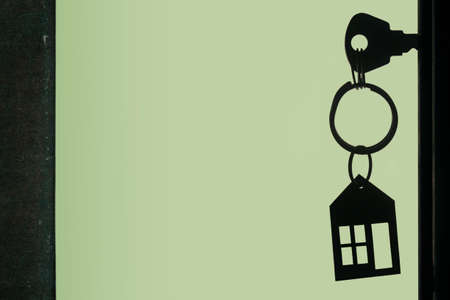 Silhouette of the keys with keyring in the door keyhole on the green backgroundの写真素材