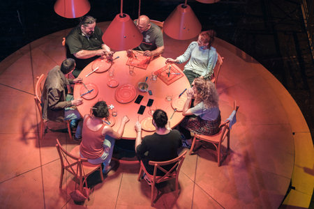 Batumi, Georgia, October, 18, 2021: A theater performance of a group of people sitting by the round table with cutlery under the red lightsのeditorial素材