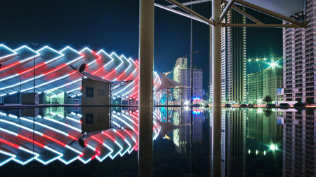 Batumi, Georgia, October, 27, 2021: View of the colorful illuminated stadium and night city with modern architecture reflecting on the water surfaceのeditorial素材