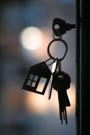 The set of  keys with keyring in the door keyhole with blurred night lights background, selective focusの写真素材