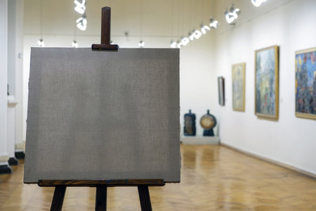 An empty painting canvas on the wooden easel with blurred gallery background, selective focusの写真素材