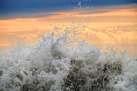 Foamy sea waves splashing, stormy sunset backgroundの写真素材
