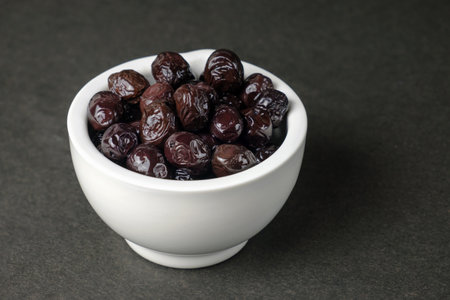 black olives in a white porcelain bowl on dark backgroundの写真素材