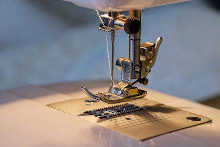 Close up shot of sewing machine steel foot with needle and thread, selective focusの写真素材