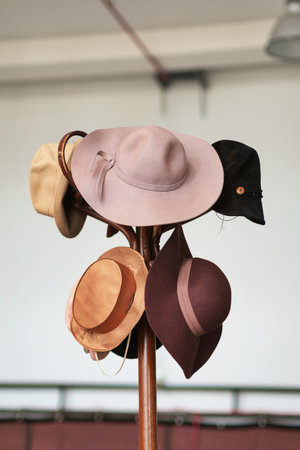 A variety of vintage colorful hats hanging on the wooden brown coat rackの写真素材
