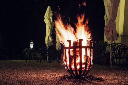 Burning fire flames pit steel basket in darkness in the yardの写真素材