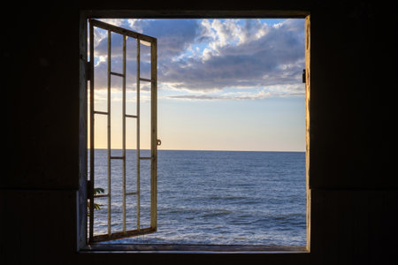 View of a seascape from the window with cage in an in the dark roomの写真素材