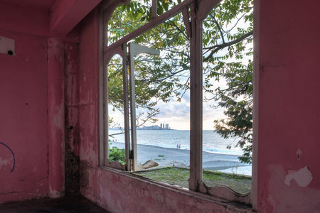 View of a seascape from broken window in an abandoned house with pink wallsの写真素材