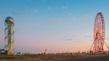Metal tower and  ferris wheel on a daybreak with blue cloudy sky backgroundの写真素材