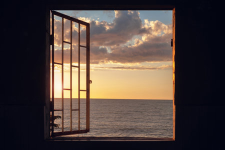 View of a sunset seascape from the window with cage in an in the dark roomの写真素材