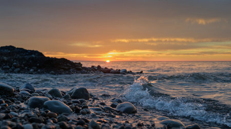 Soft sea waves washing rocky beach on sunsetの写真素材