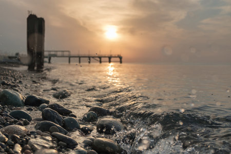 Small sea waves splashing at the beach with pebbleof at sunset, selective focusの写真素材