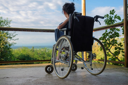 Disabled girl in a wheelchair looking at the nature viewの写真素材