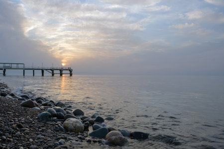 Small sea waves splashing at the beach with pebble at sunset, selective focusの写真素材