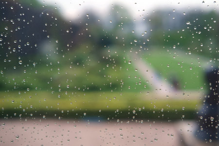 Rain drops on a window glass looking onto a garden, selective focus